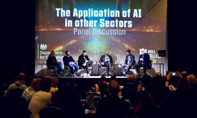 Panelists seated on stage discuss AI applications, under the title "The Application of AI in other Sectors," with an audience watching attentively.