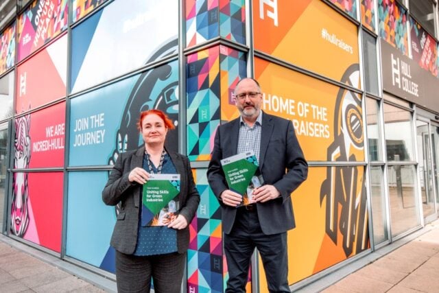Two people stand outside a colourful building with murals and text promoting Hull College. They hold brochures titled "Uniting Skills for Green Industries."