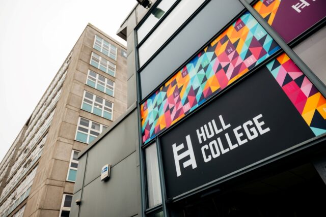 Modern building with vibrant geometric patterns and "Hull College" text. Adjacent is a taller, grey structure with large windows, under an overcast sky.