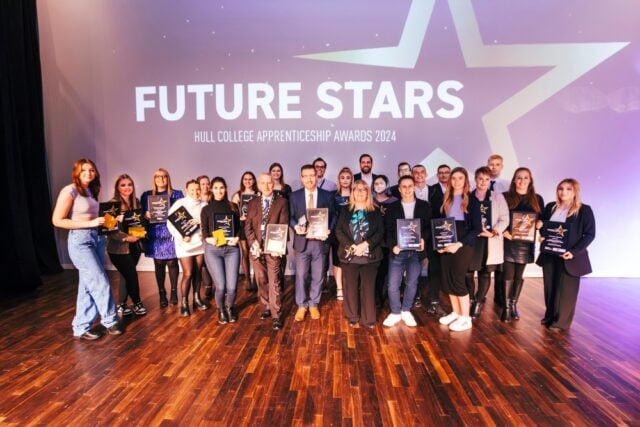 Group of award recipients stand proudly on stage holding plaques and trophies at the Hull College Apprenticeship Awards 2024. The backdrop reads "Future Stars."