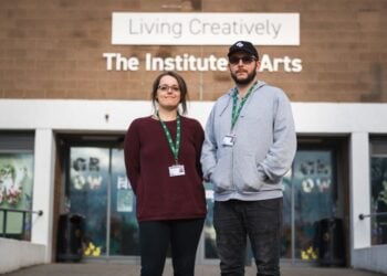 Two people stand confidently outside a building labelled "The Institute of Arts," conveying a sense of creativity and professionalism.