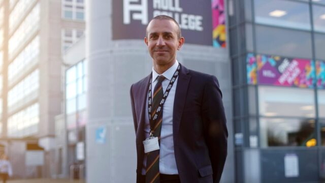 A man in a suit stands confidently outside a building with "HULL COLLEGE" signage. The scene is bright and modern, conveying professionalism.