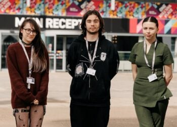Three students standing in front of a colourful building labelled "Main Reception."