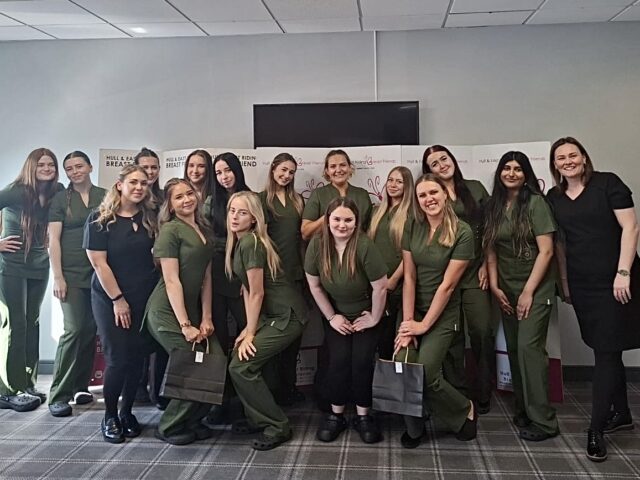 A group of women, mostly in green scrubs, pose for a cheerful photo at a charity event for Hull & East Yorkshire Breast Friends.