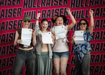 Four students hold certificates and raise their fists joyfully against a bold “Hullraisers” backdrop.