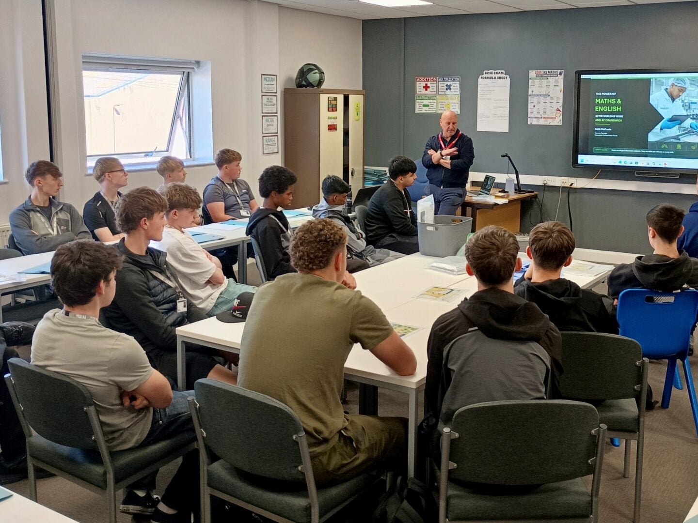 Students gather in a classroom as an instructor presents workplace safety information on a screen, creating an attentive, educational atmosphere.